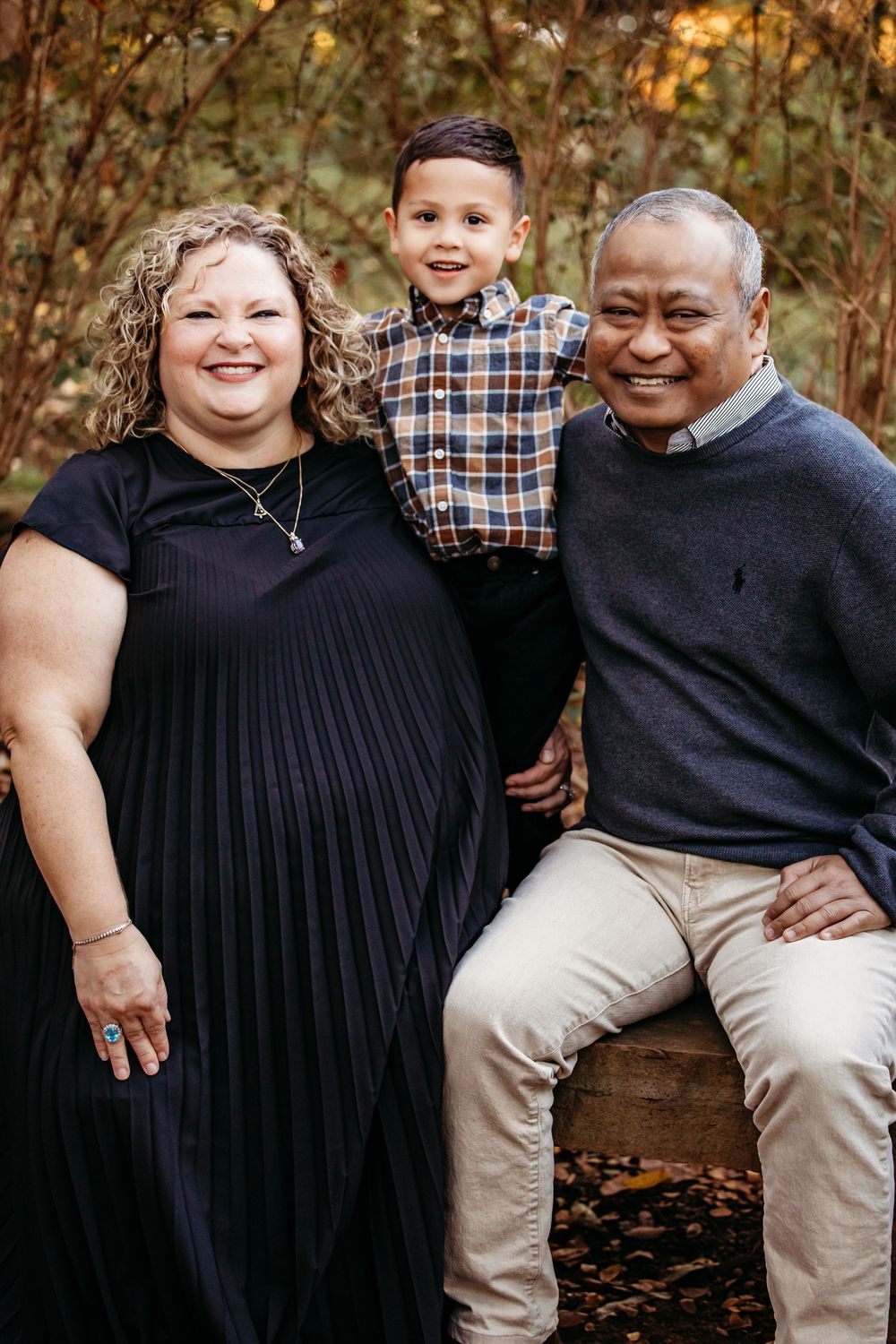 A family sits together outdoors in coordinated black and plaid outfits during an autumn photoshoot.