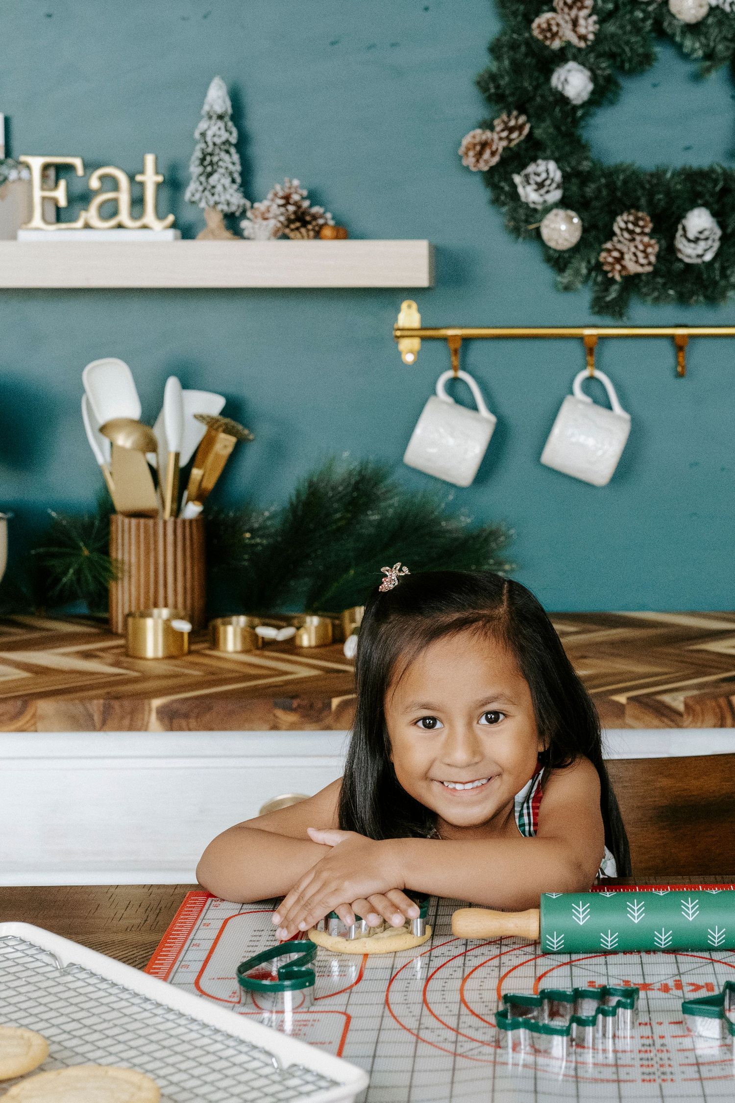 A child lies on a wooden floor with holiday decorations and greenery visible in the background.