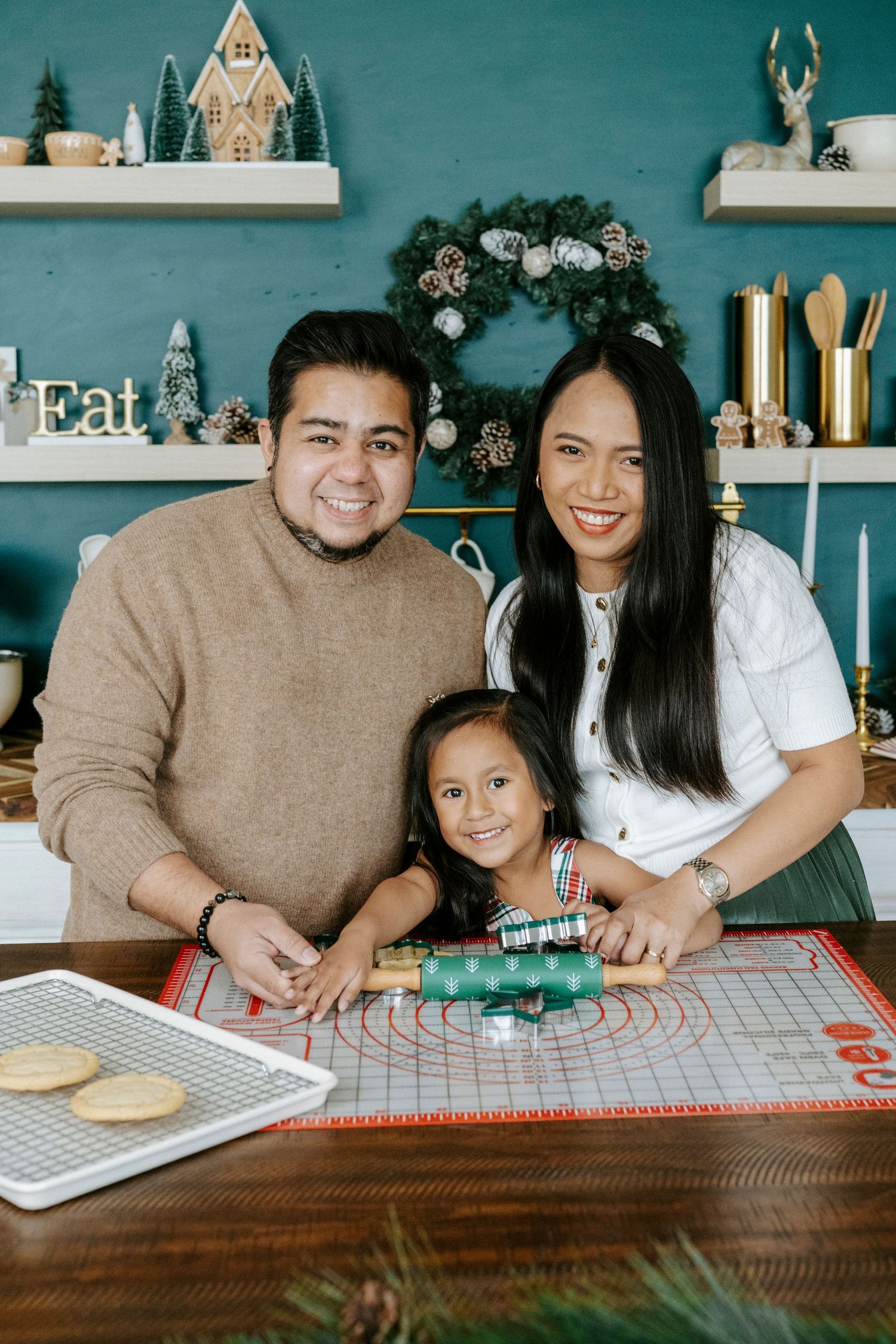 A family gathers around a wooden table with holiday decorations, sharing a festive moment together.