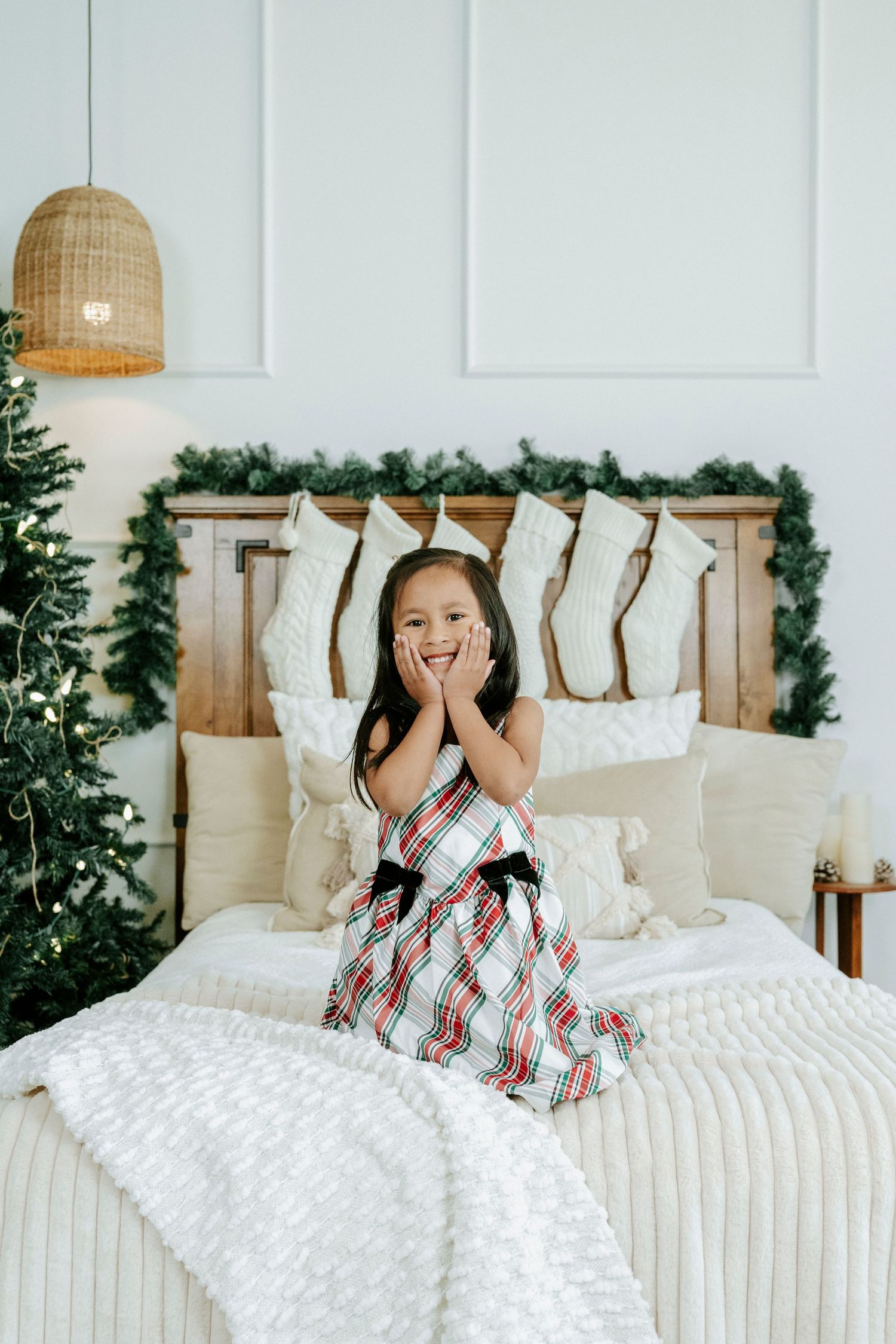 Joyful holiday scene with white bedding and greenery decorations in a bright bedroom setting.