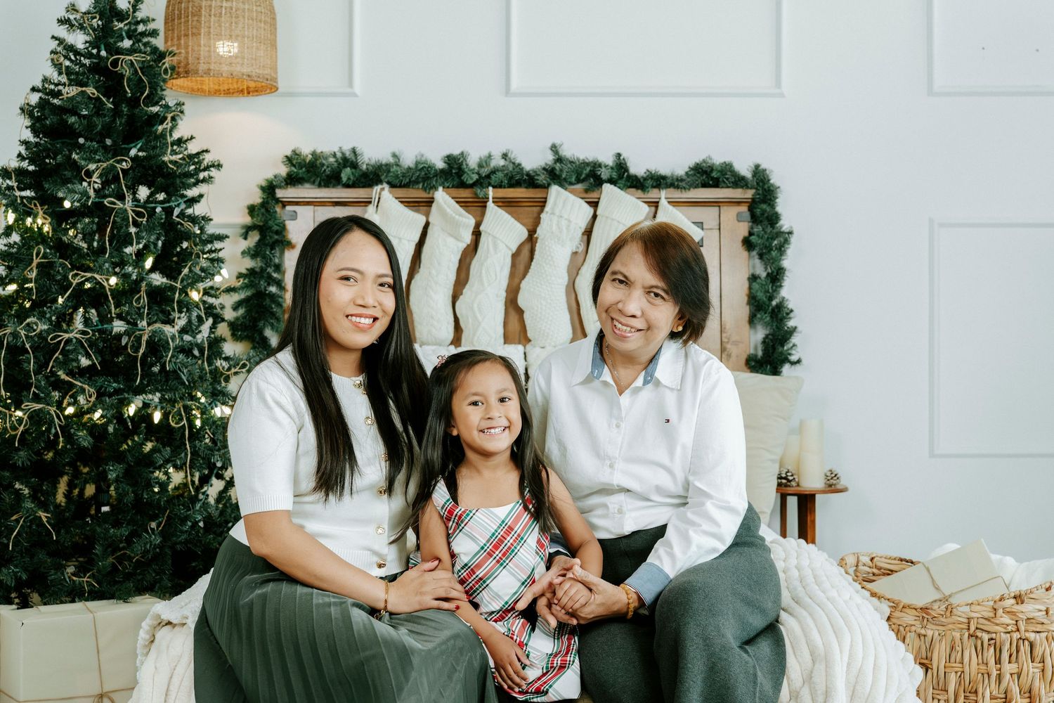 A family wearing white and denim sits together on a couch during a holiday photo session.