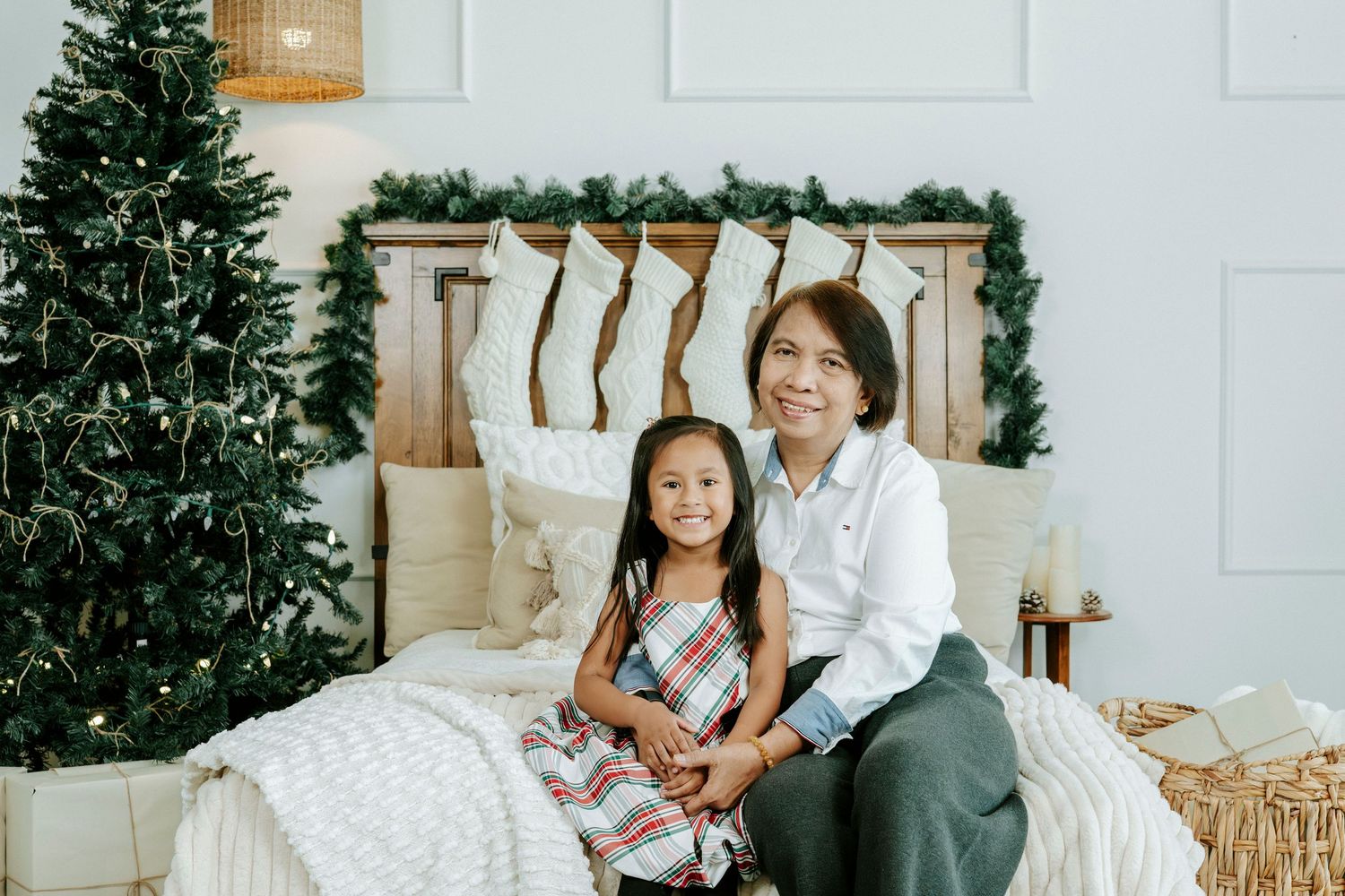A family sits together in a festive holiday setting with a Christmas tree and white decor.