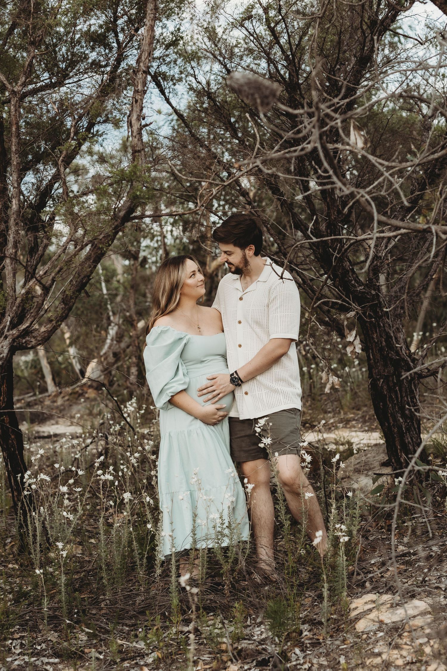 Intimate family photo session among trees with soft earth-toned clothing.