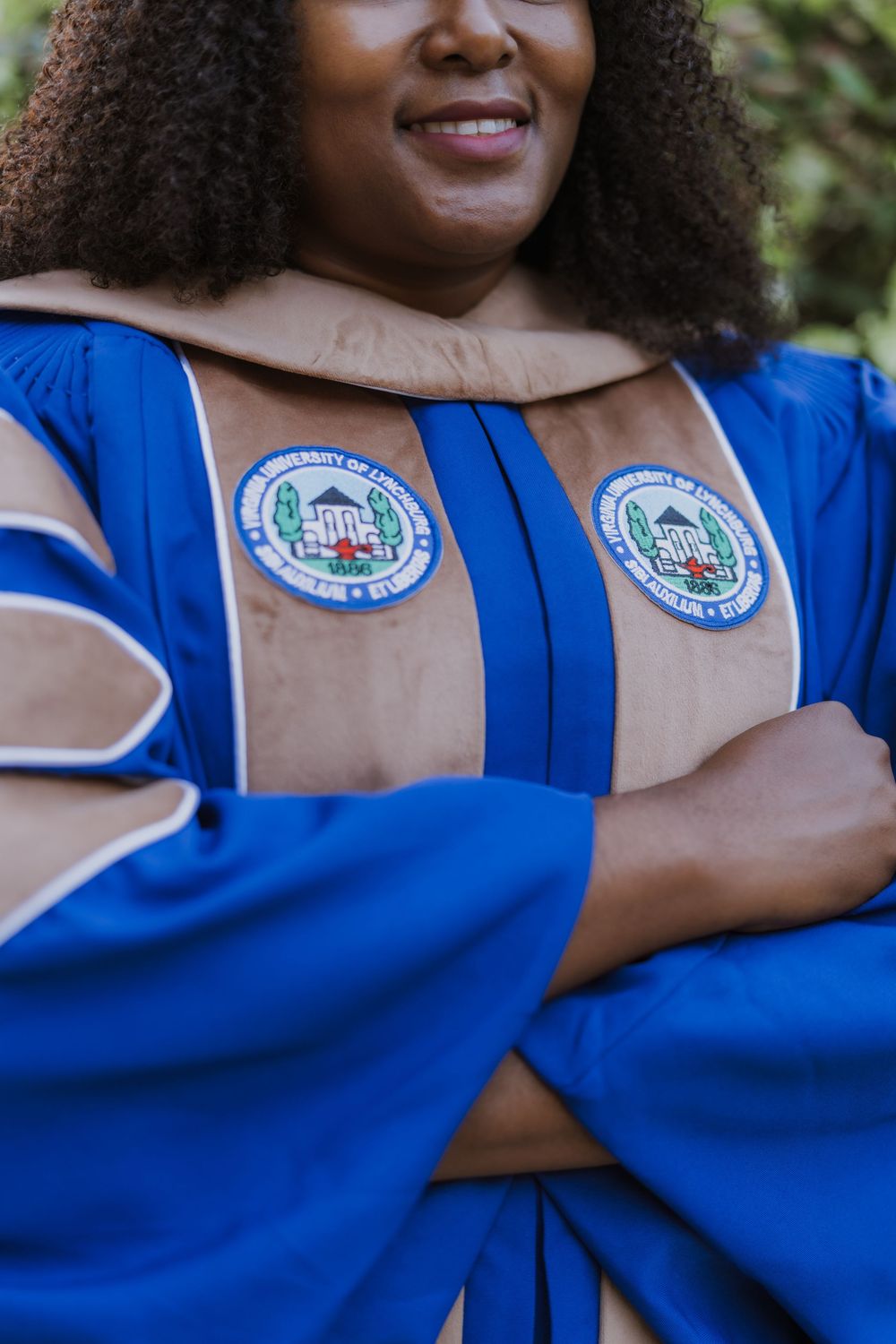 Academic regalia showing blue and tan graduation robes with university seal patches.