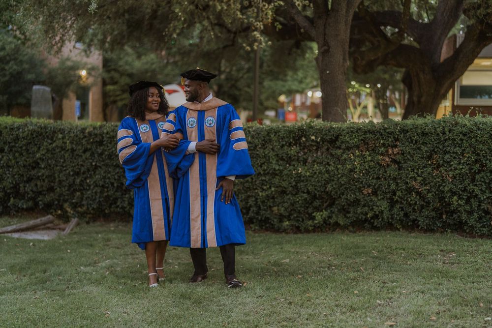 Graduates in matching blue and gold academic regalia standing together on university grounds.