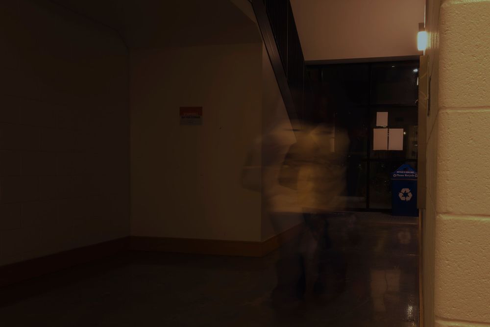 Dark interior hallway with minimal lighting creating atmospheric shadows.