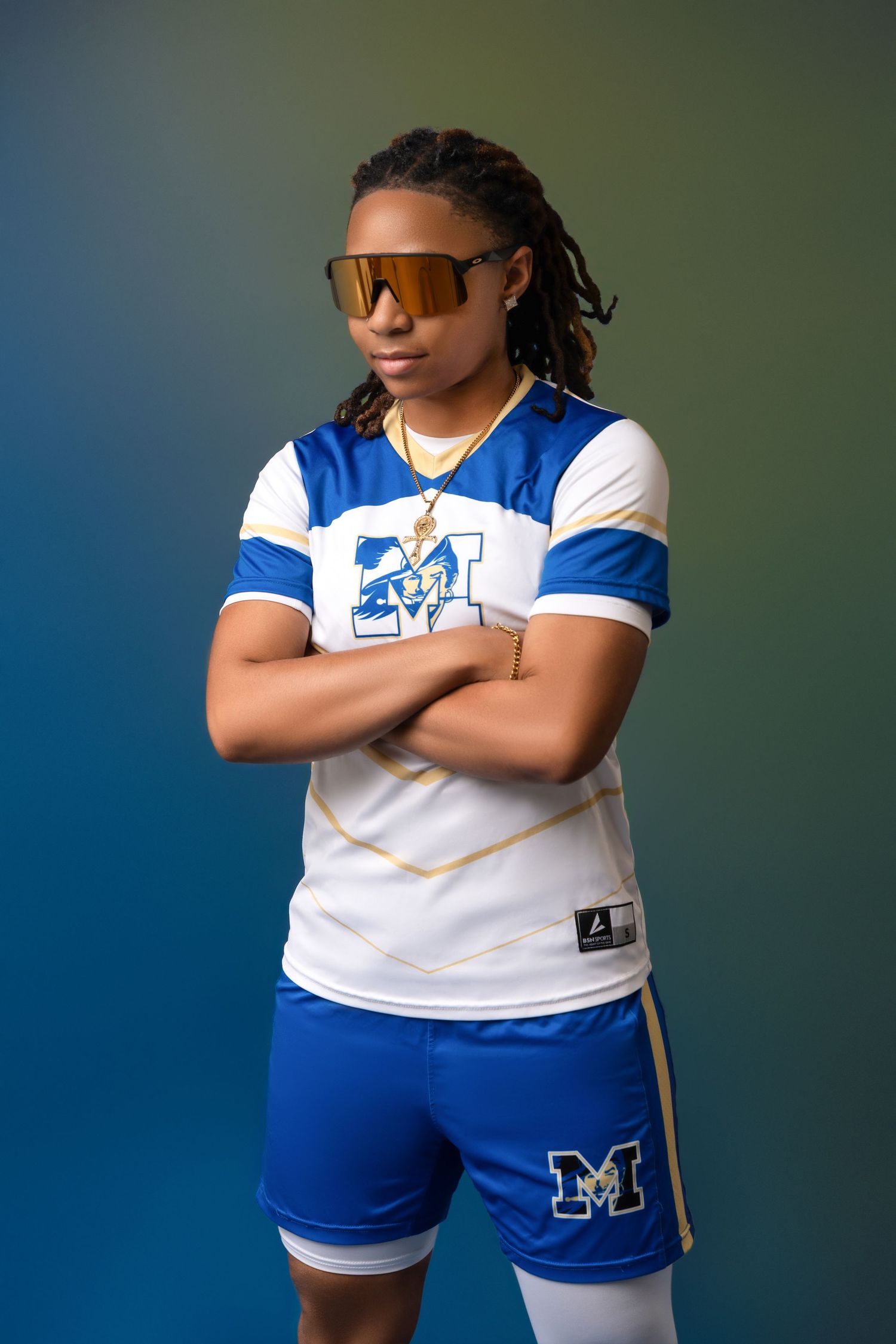 A person in blue and white athletic wear stands with crossed arms against a blue background.