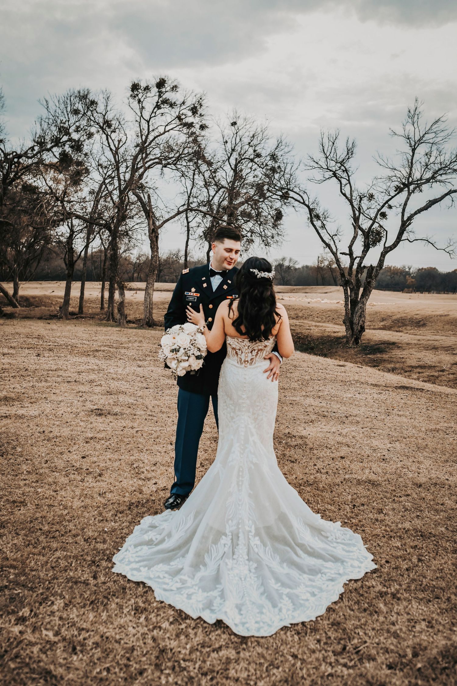 Elegant editorial portrait of the couple standing in sweeping ranch scenery at sunset.