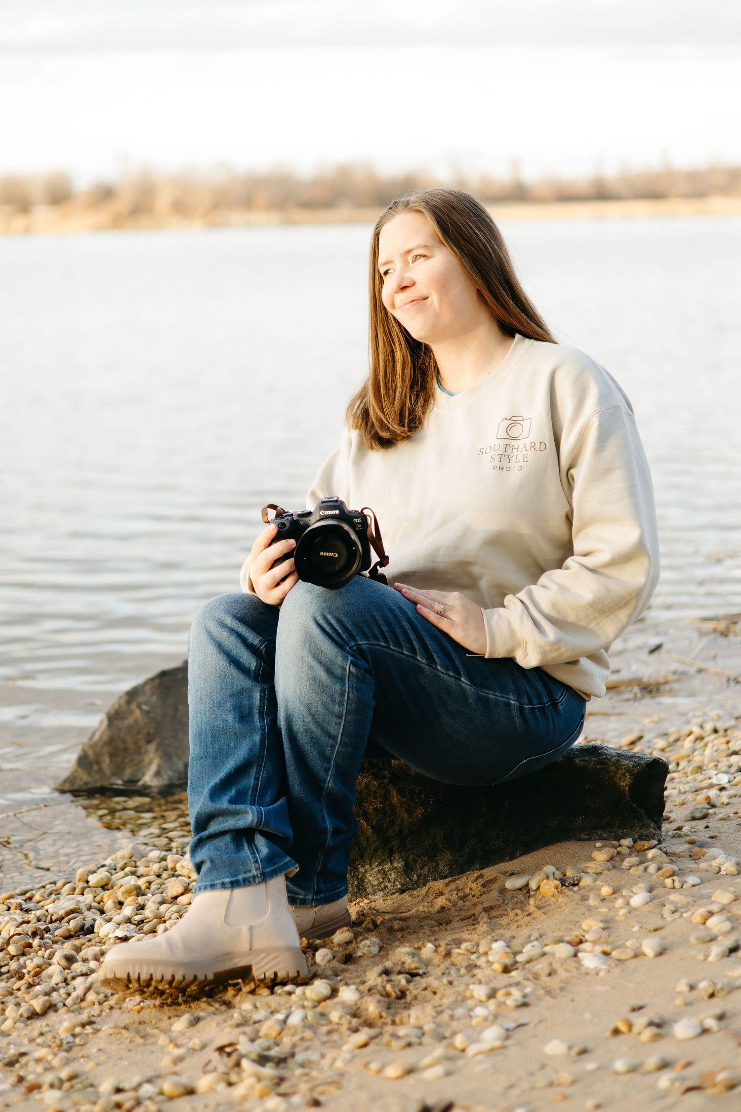 A person in a cozy sweater and jeans stands in tall grass during golden hour.