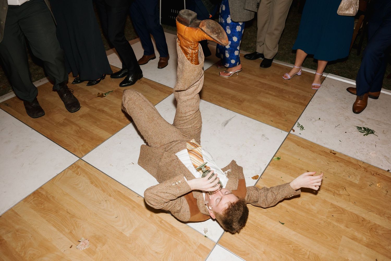 Dancing feet on wooden floor during wedding reception celebration.