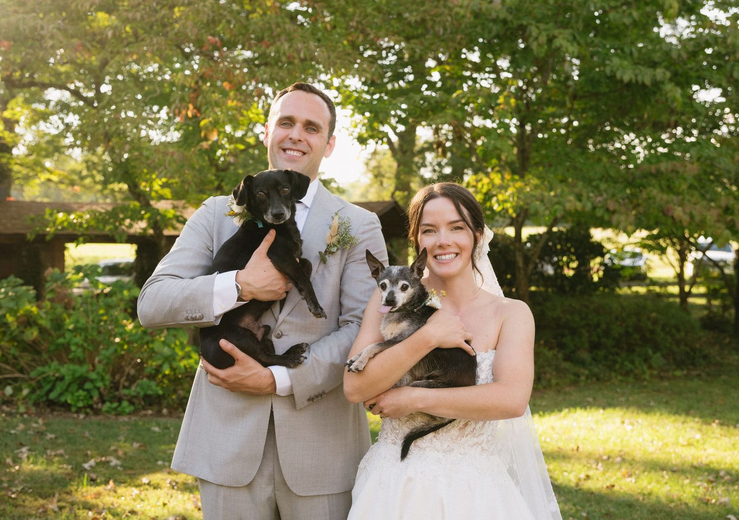 Wedding couple and attendants posing for photos in a sunlit garden setting.