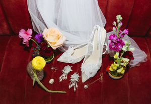 Elegant wedding floral arrangements featuring pink and peach roses with white accents against a deep burgundy background.