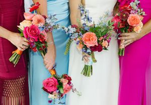 Bridesmaids in light blue dresses holding vibrant pink and coral bouquets at a wedding ceremony.