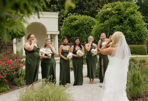 Wedding party posing in front of a garden with blooming red roses.