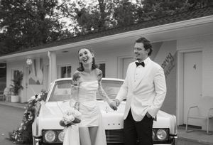 Wedding party in white tuxedos gathered outside a classic white building.