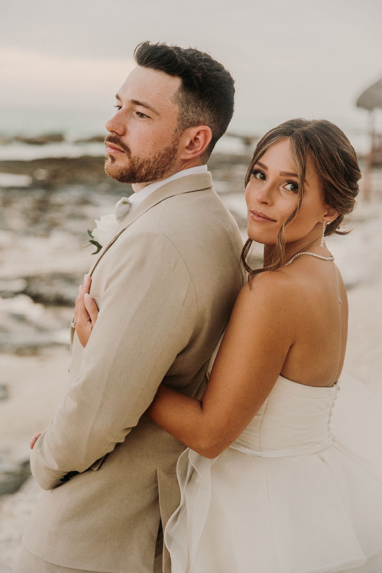 A romantic beach wedding photoshoot featuring a couple embracing in warm neutral tones at sunset. El Dorado Royale Wedding Photographer