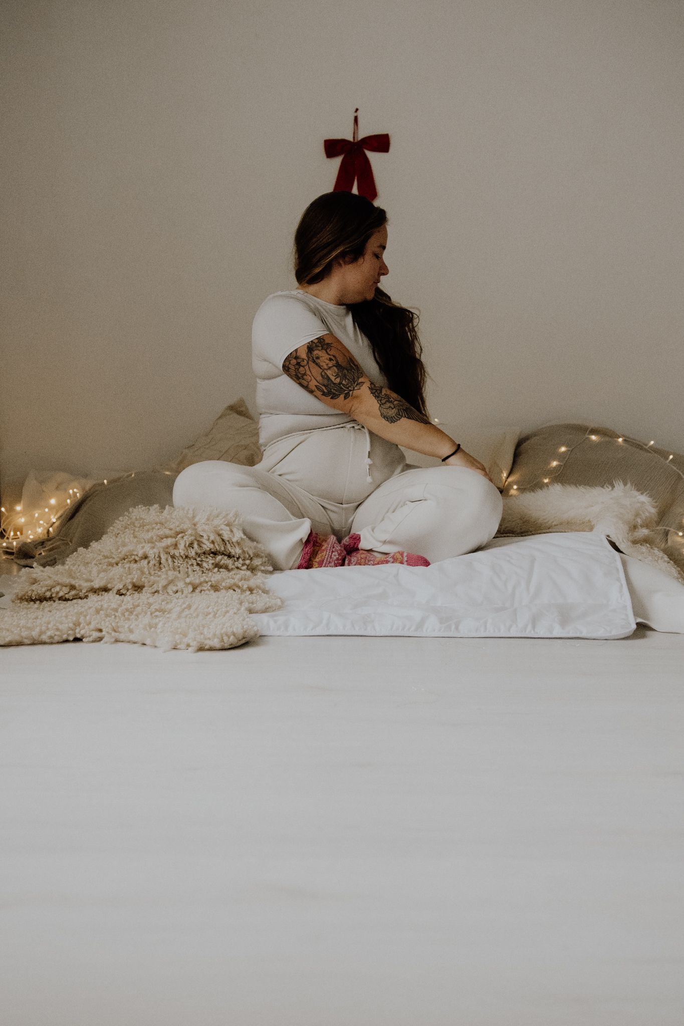 A series of minimalist photos showing two people lying together on white bedding in soft, muted lighting.