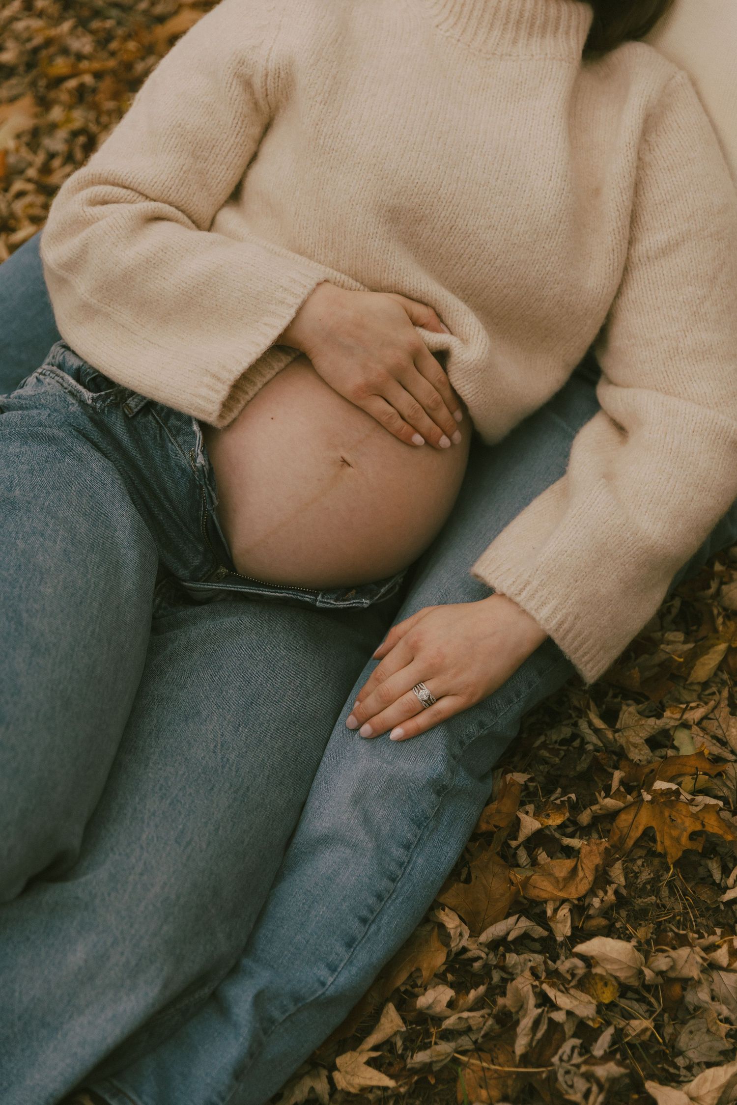 A person wearing a beige sweater and blue jeans sits on fallen autumn leaves in an artistic cropped photo series.