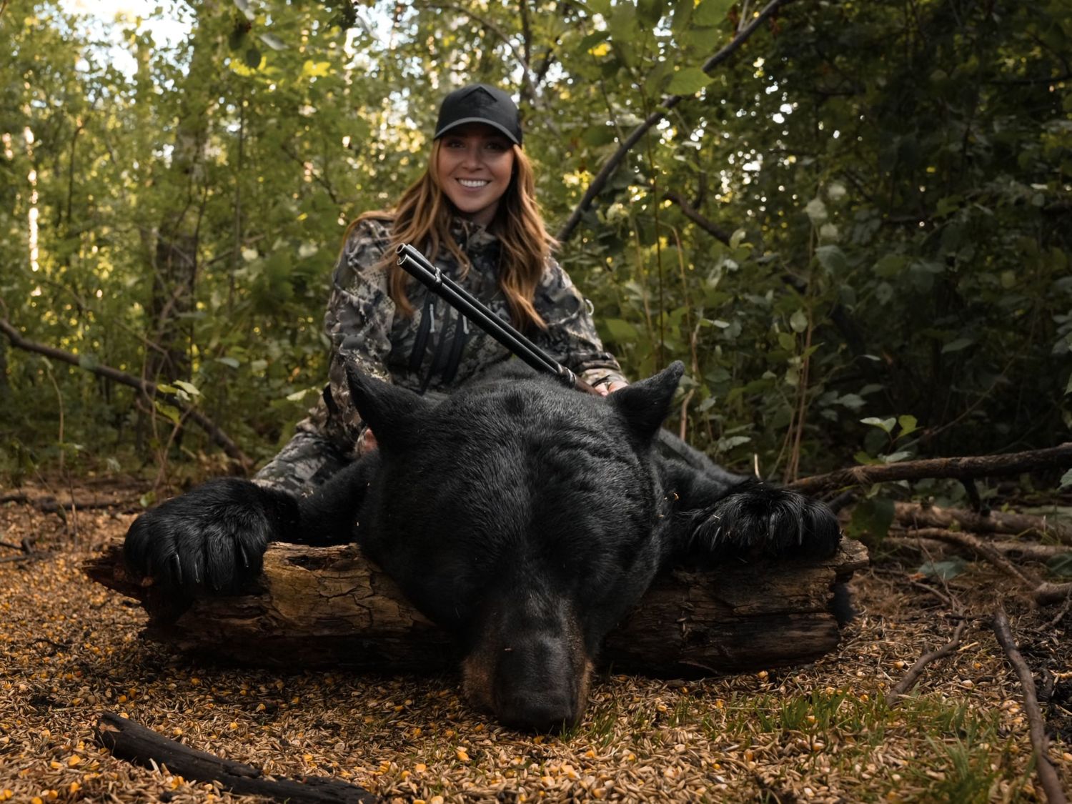 Black bear resting on fallen log in autumn forest setting.