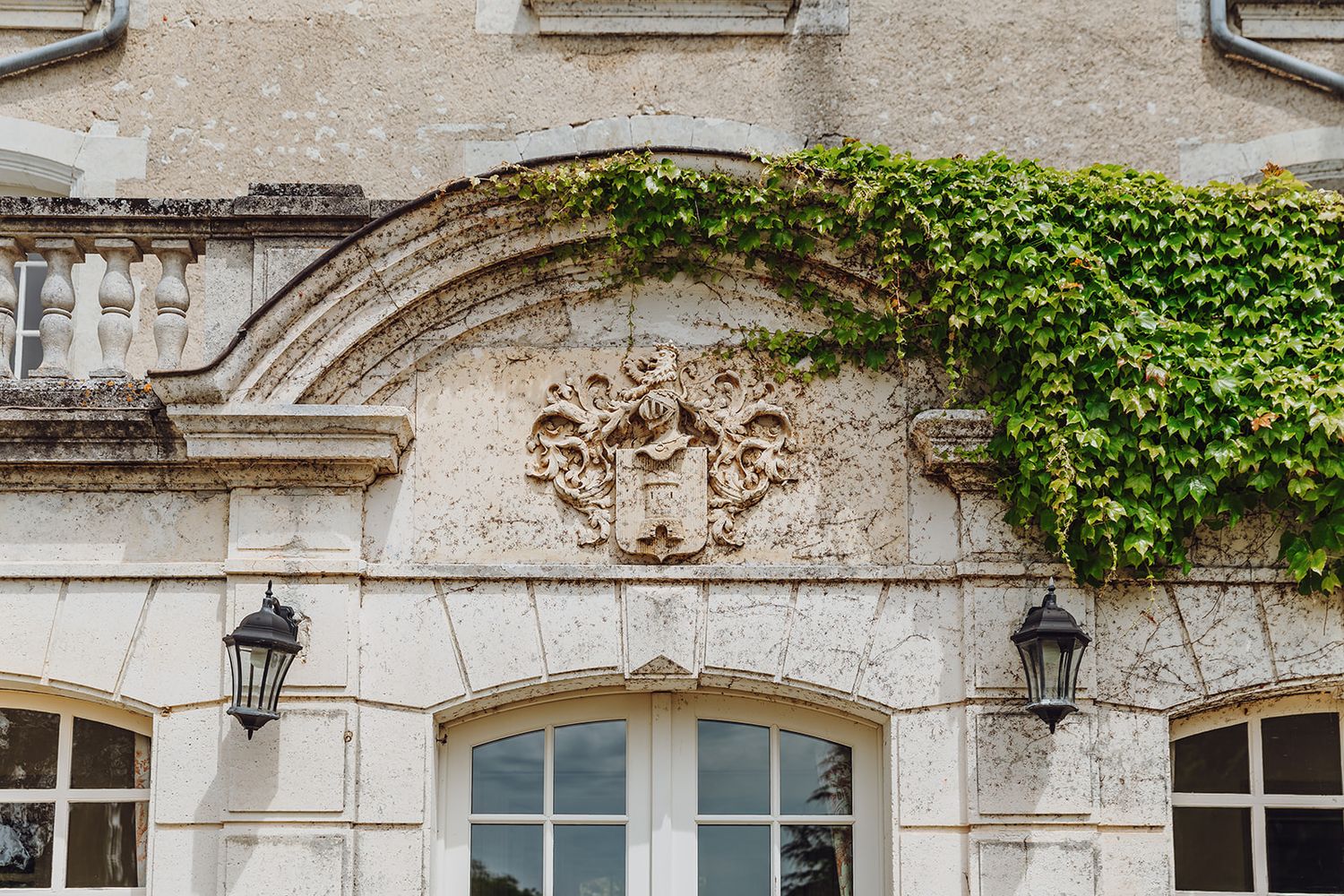 Ornate stone facade of a historic building with climbing ivy and decorative architectural details.