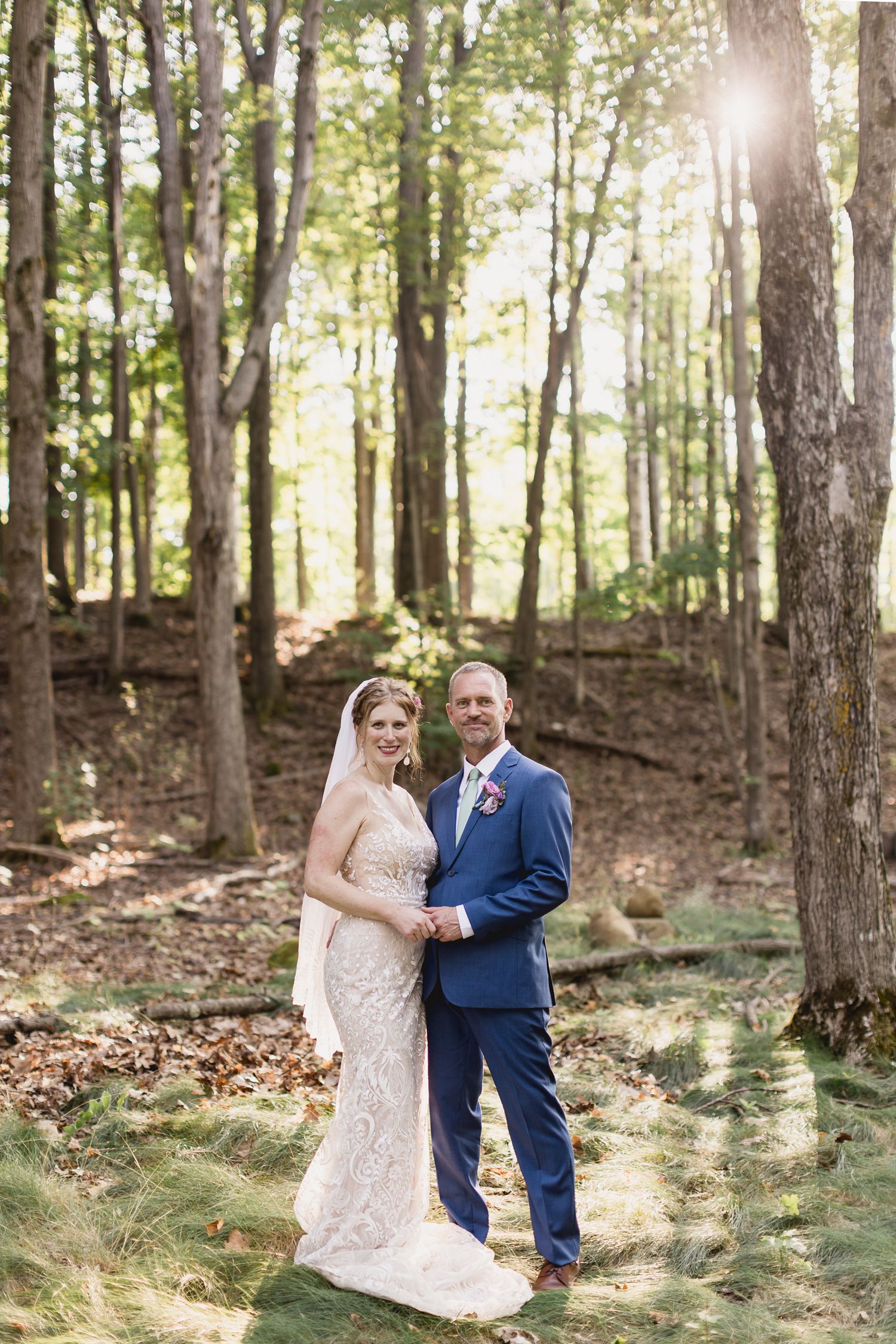 Three wooden directional signs with arrows pointing to a wedding ceremony in a lush green forest setting.