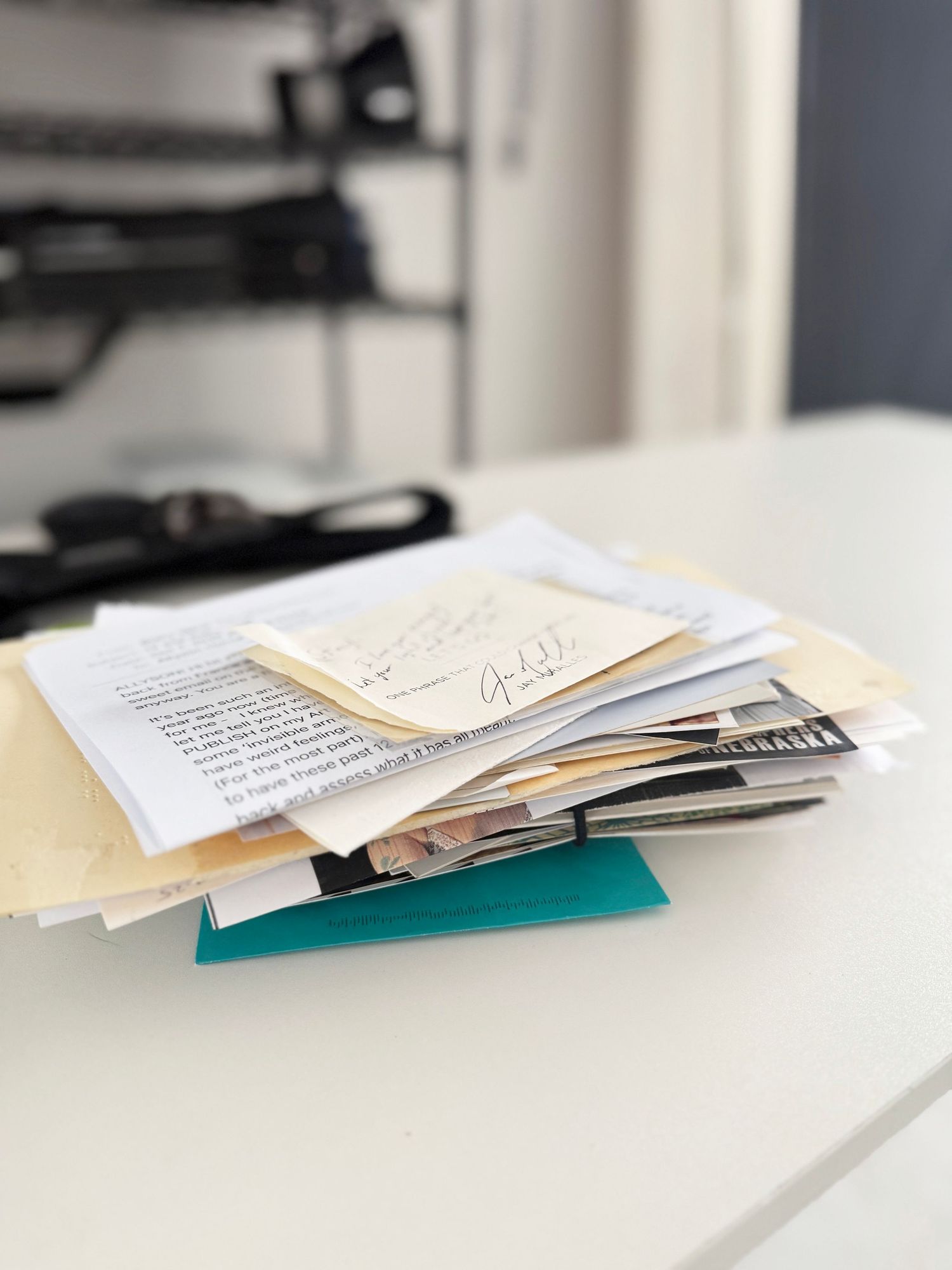 A stack of papers and documents lying on a white surface shown from different angles in a minimalist setting.