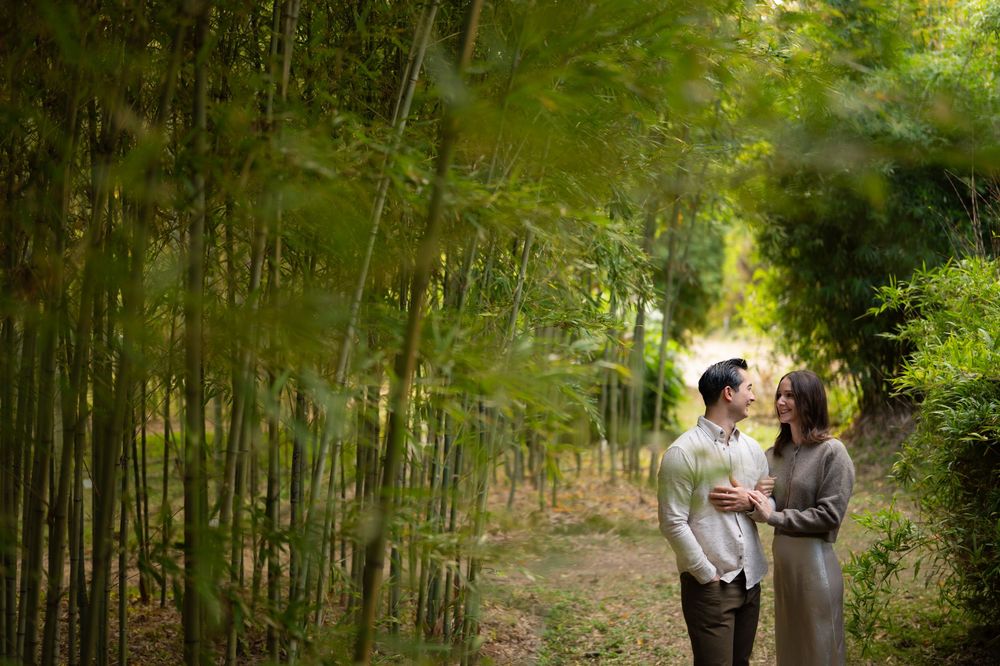 Couple sharing a romantic moment together on a bamboo forest path, framed by lush green bamboo leaves.