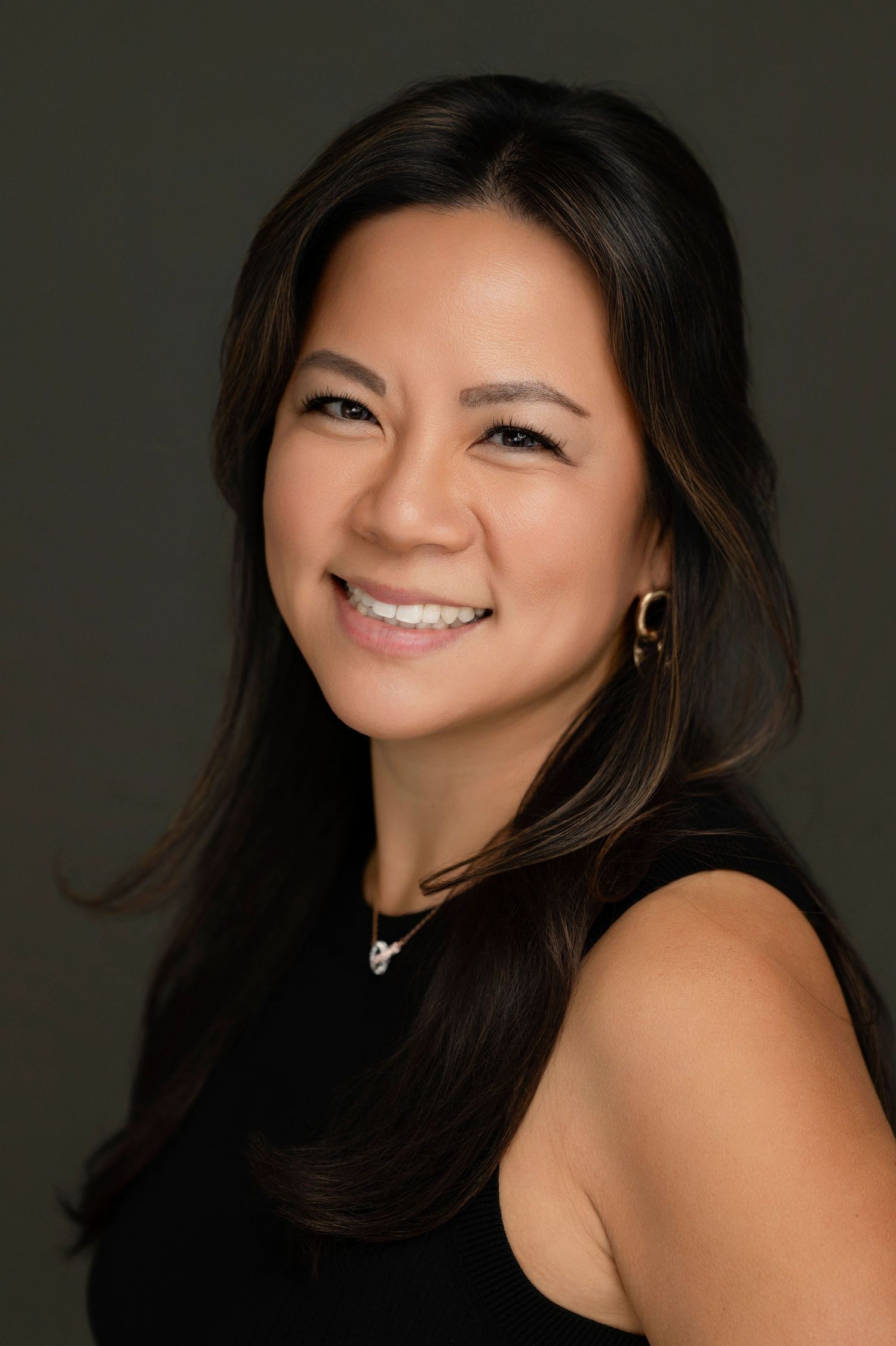 Professional studio headshot against dark background with warm lighting.