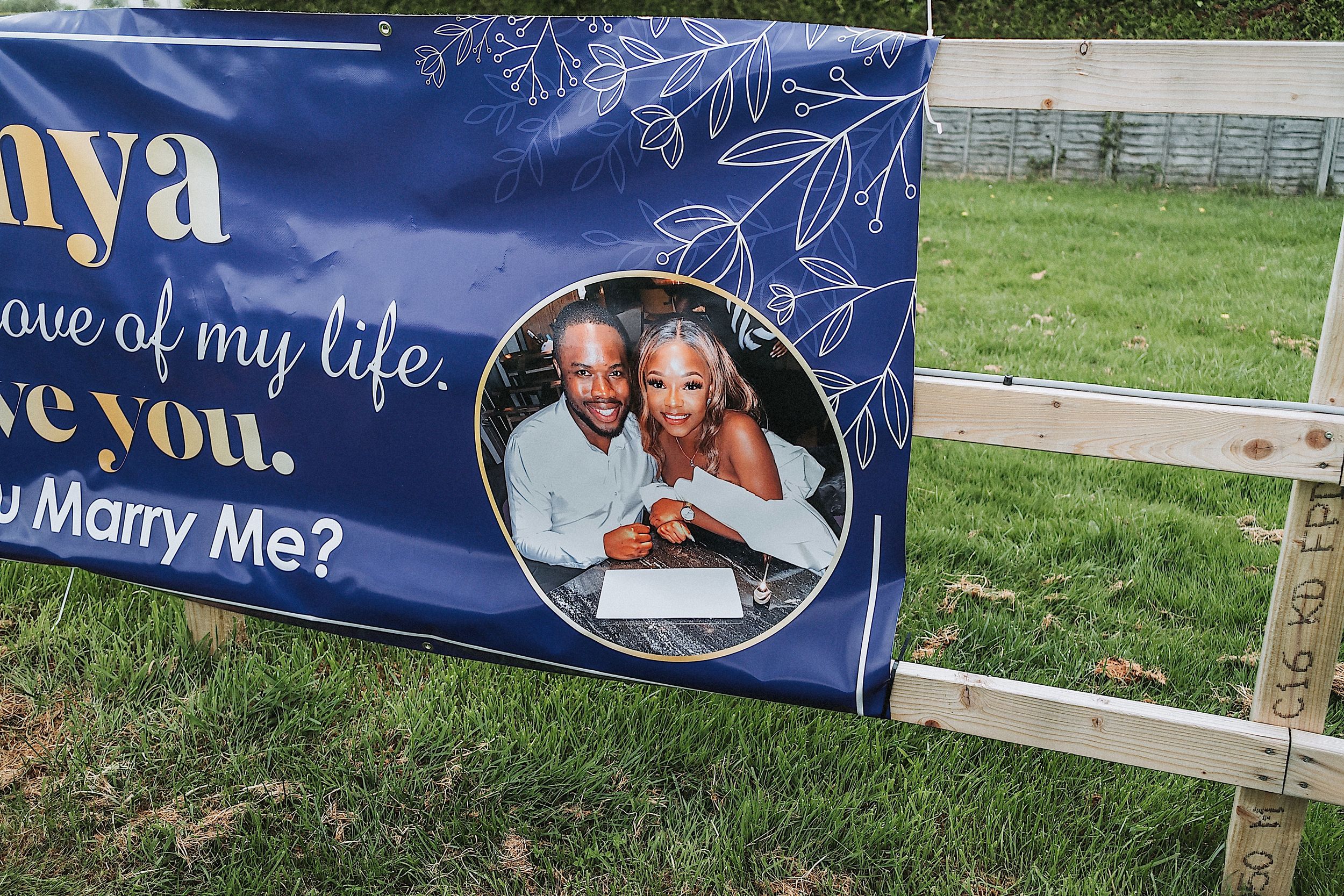 A series of blue banners with text and photos displayed outdoors in a grassy area creating a romantic display.