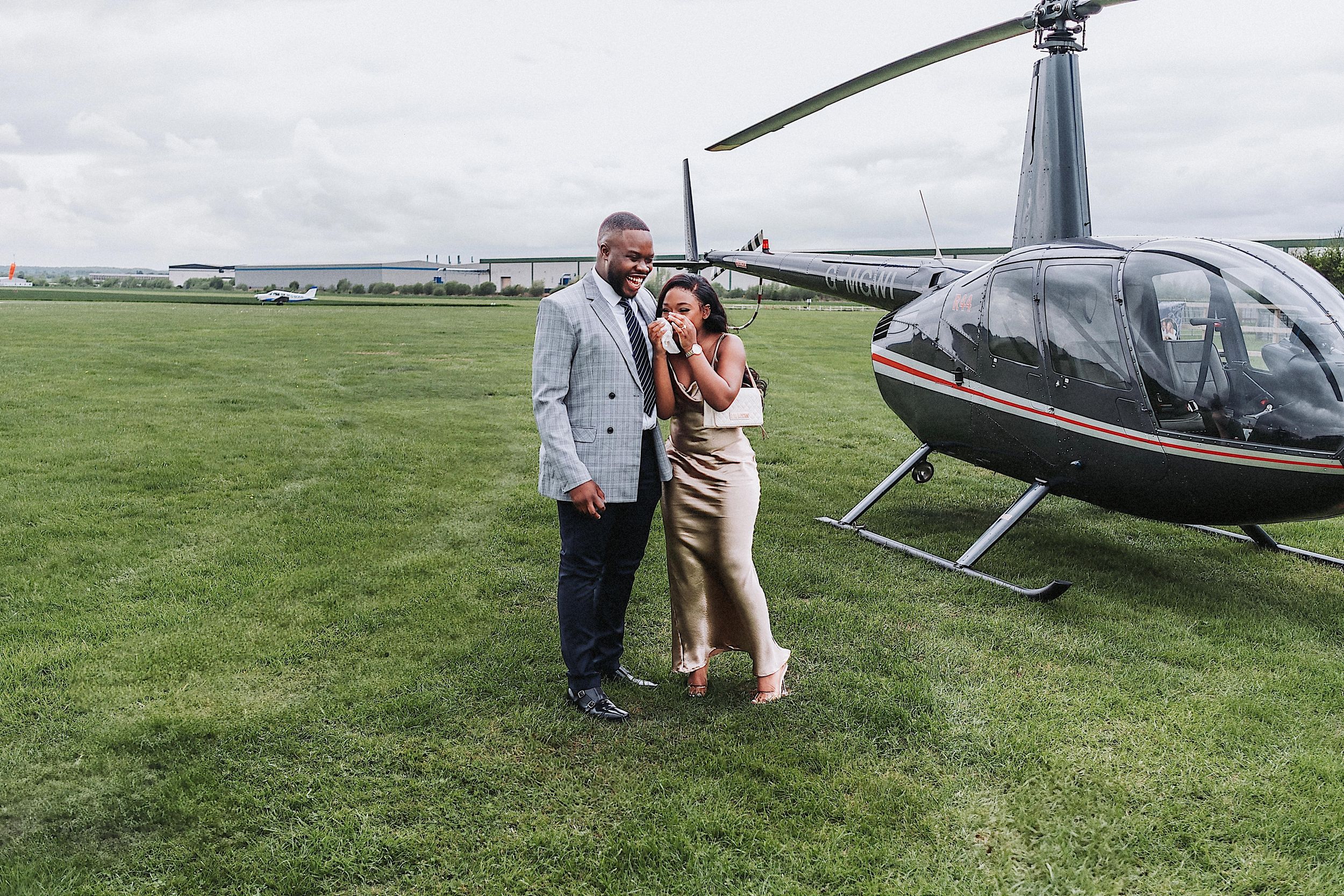A series of romantic moments captured at a helicopter landing site on a grassy airfield.