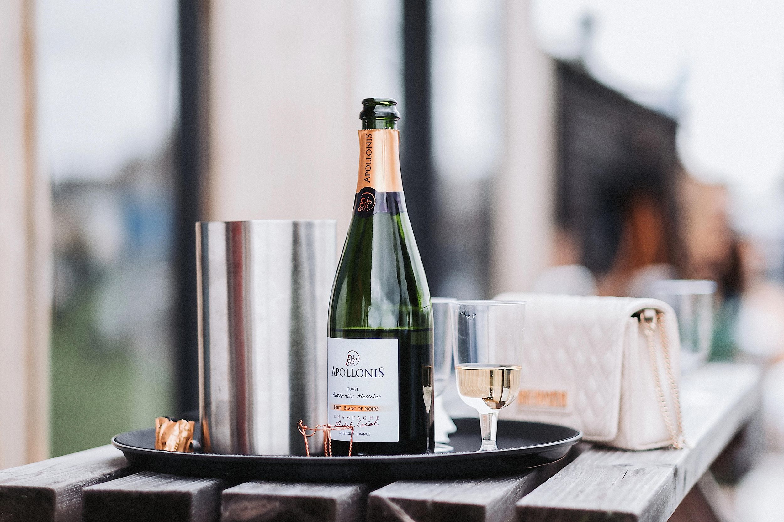 Wine glasses and champagne bottles arranged on a dark serving tray at an elegant event setting.