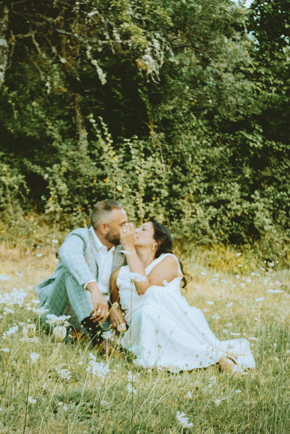 Romantic garden engagement session featuring a couple sitting together in a natural outdoor setting.
