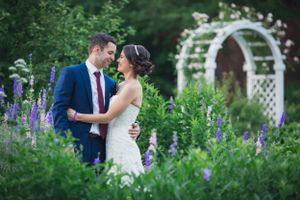 Elegant bride and groom lovingly gaze at each other in a flower garden