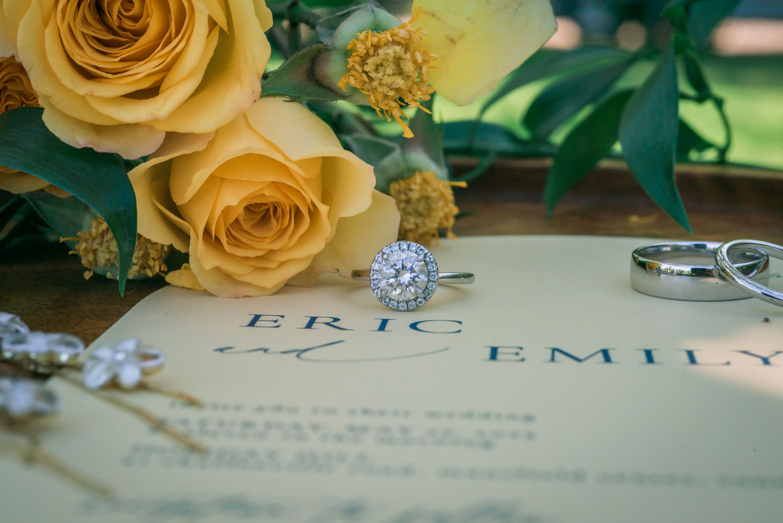 Wedding bands sit on top of invitations near flowers