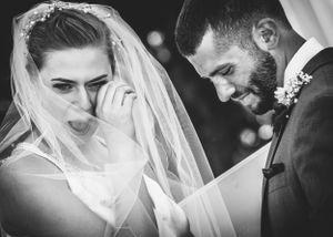 Emotional picture of bride wiping away tears and groom smiling joyfully after ceremony