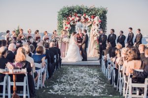 Guests watch bride and groom under flower trellis outside for a ceremony