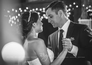 Bride and groom dance with white Christmas lights in back