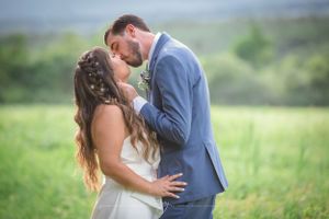 Groom leans in to kiss his newly married wife with mountains in the back