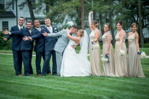 Groom dips bride as wedding party celebrate next to them