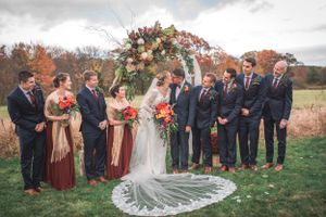 Bride and groom kiss for elegant photo while surrounded by both families