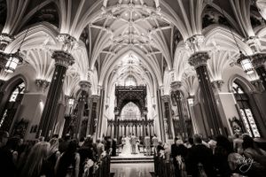 Black and white of bride and groom standing in a huge cathedral
