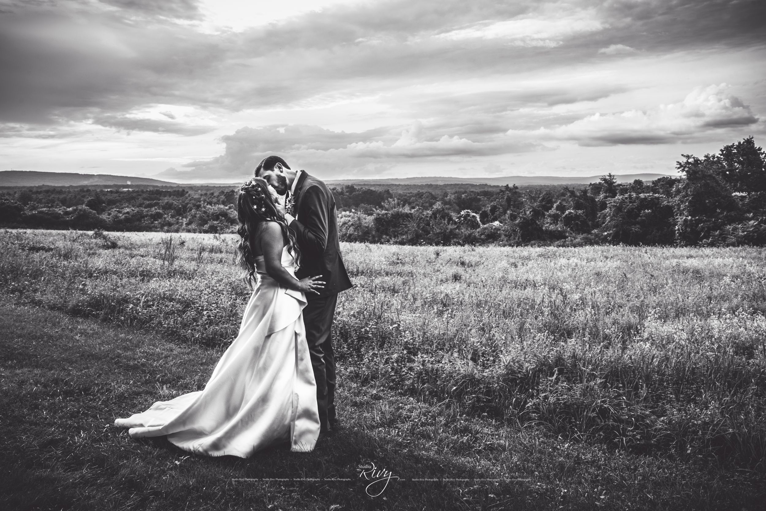 Cute bride and groom kiss with dramatic sky and mountains in back, in Connecticut.