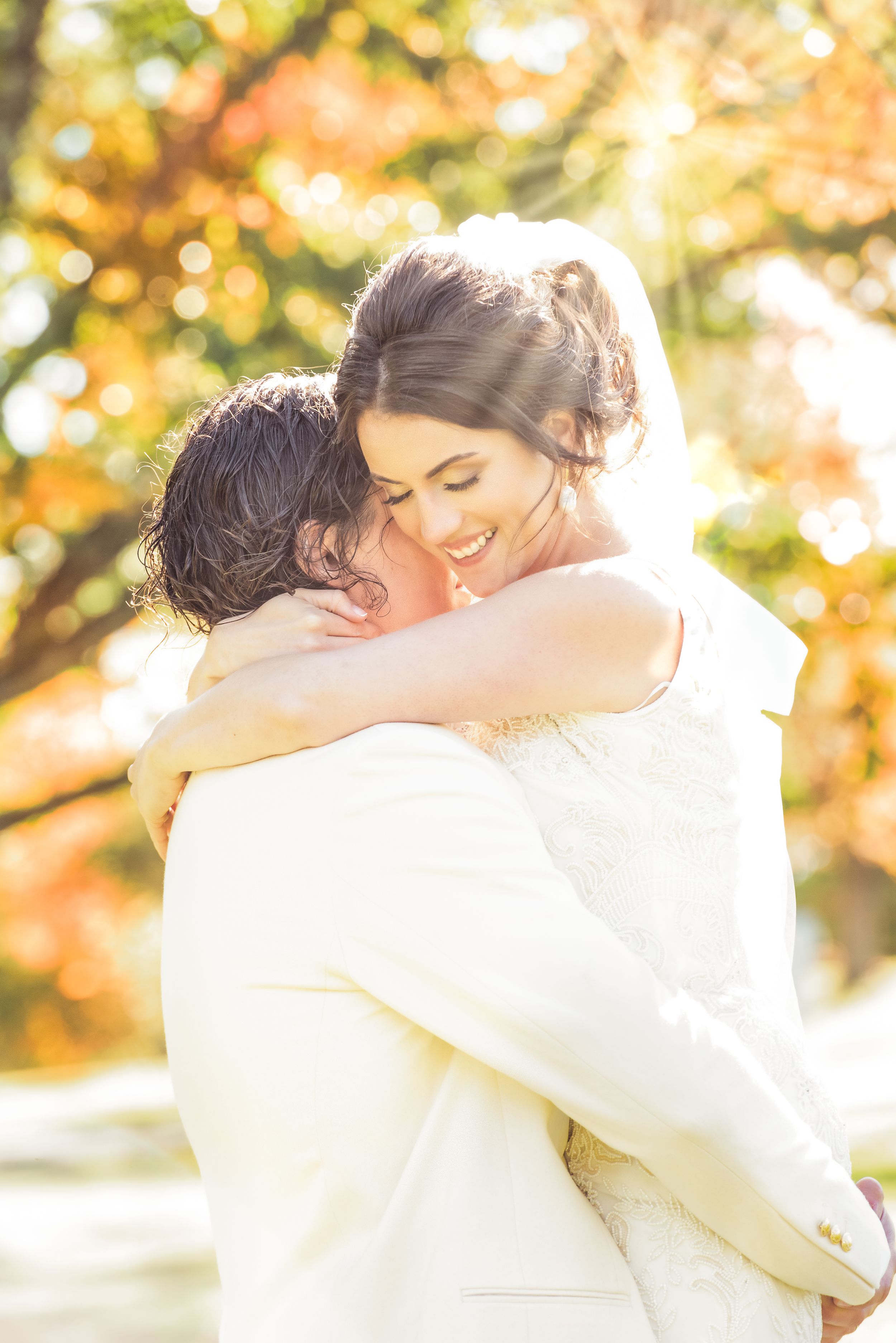 Groom hoists bride into air in jubilance after ceremony in autumn