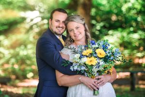 Bride and groom smile at camera with sun rays bursting in the back