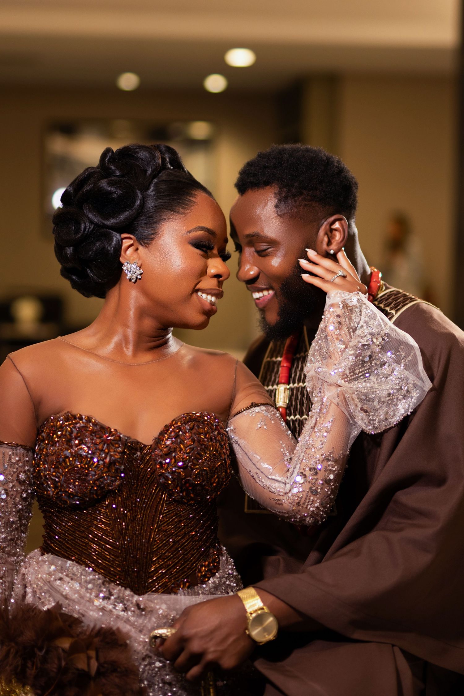 A loving couple shares an intimate moment at a wedding celebration, with bride in a glittering brown gown.