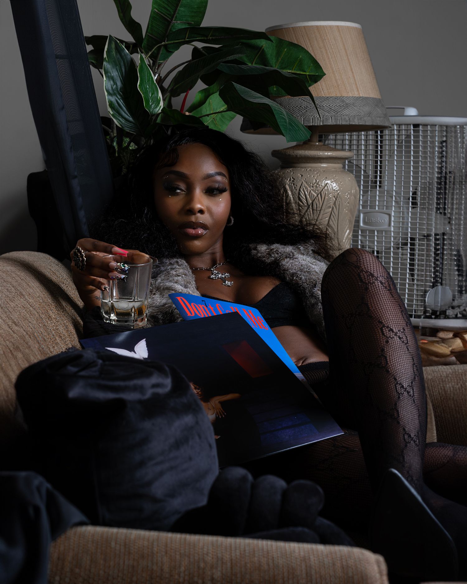 Relaxed indoor portrait on couch with houseplants and drink in casual setting.