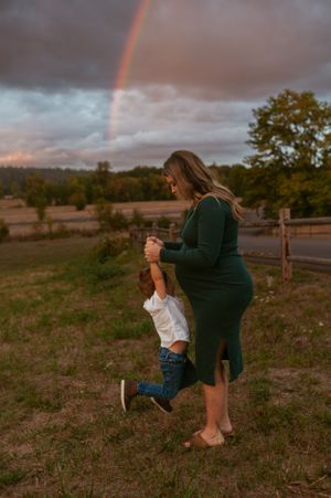 Playful family photo with rainbow backdrop during sunset maternity session.