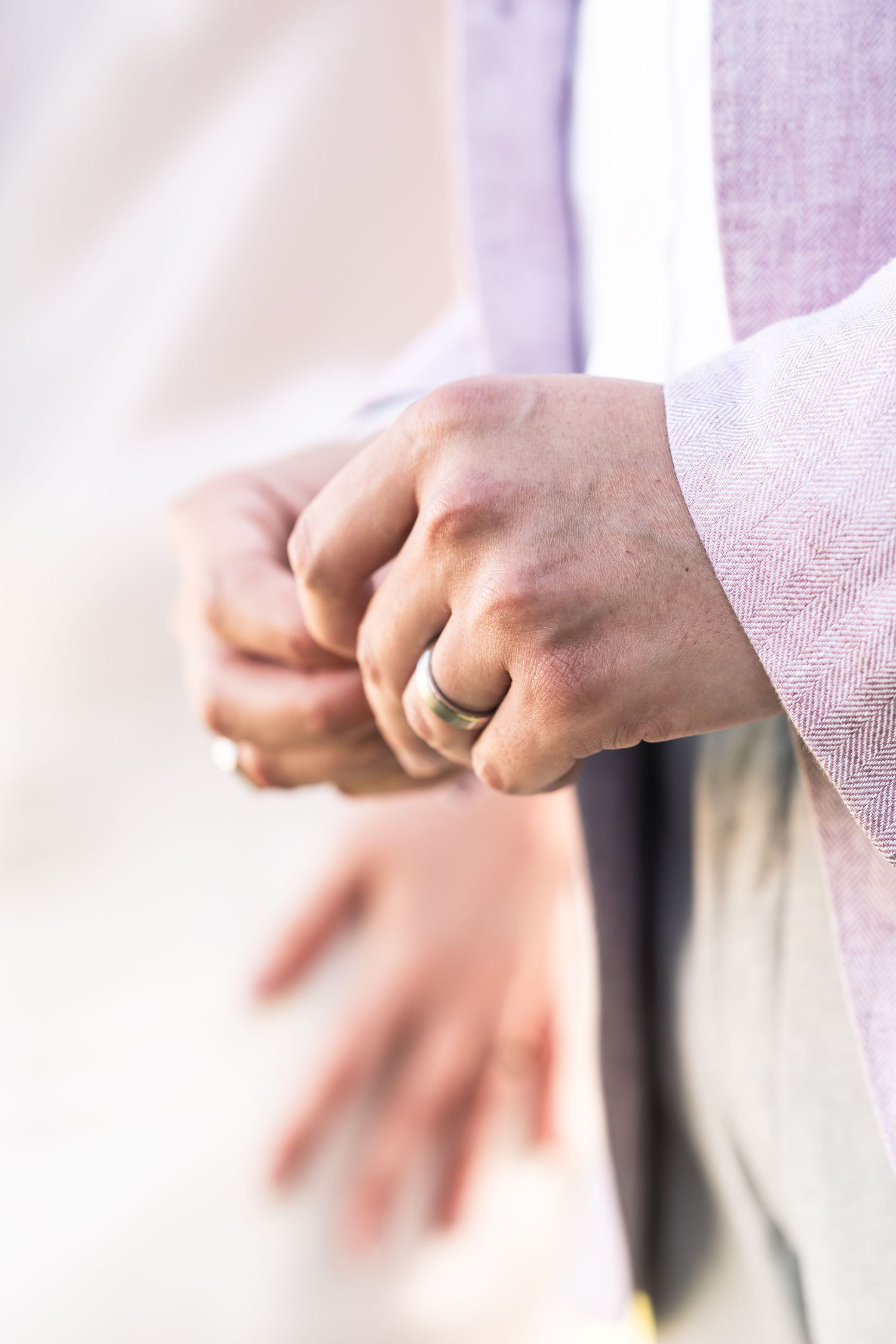 Close-up shot of hands wearing a wedding ring in soft natural lighting.