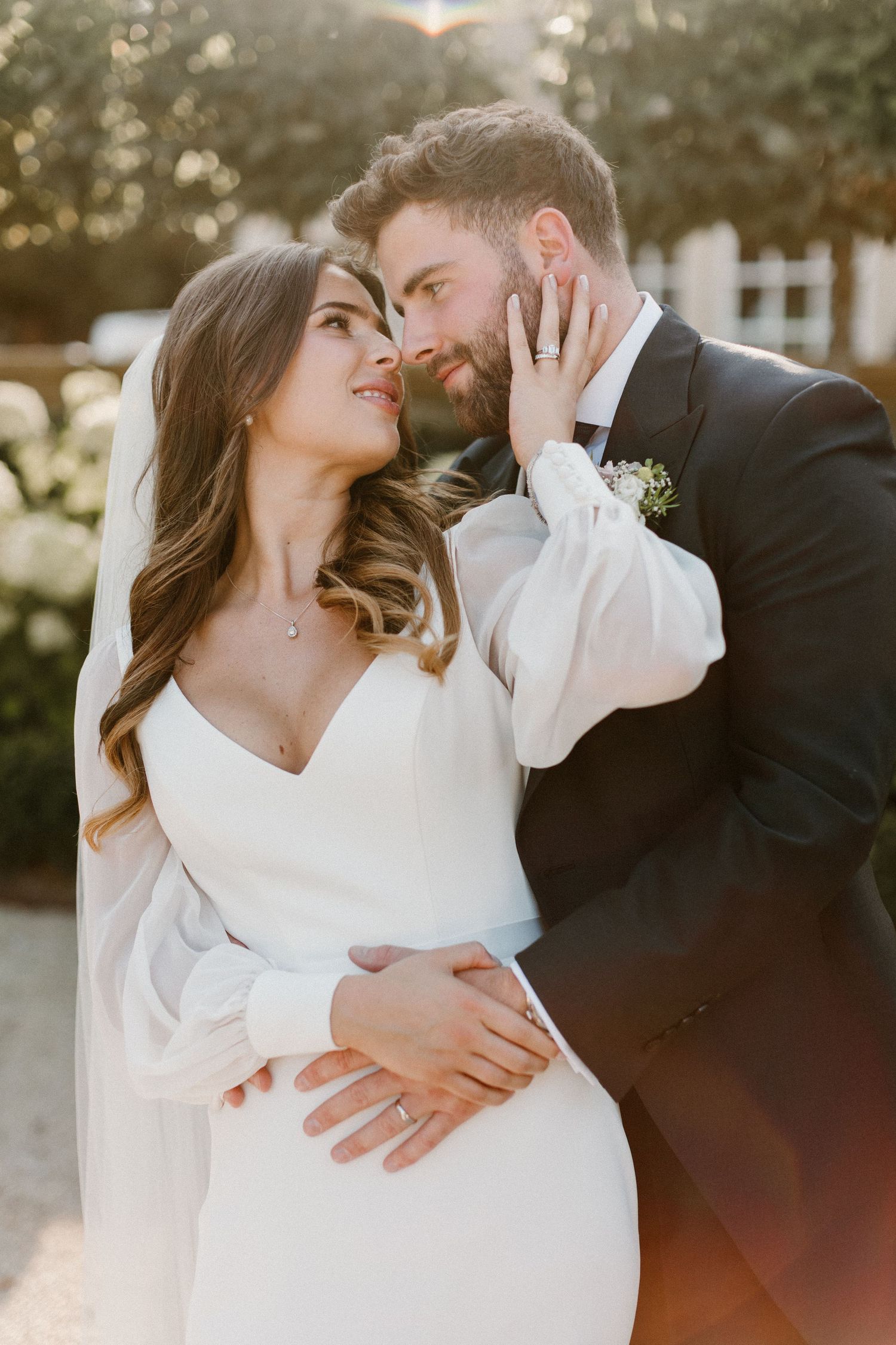 Romantic sunset wedding portrait of couple embracing in warm light.