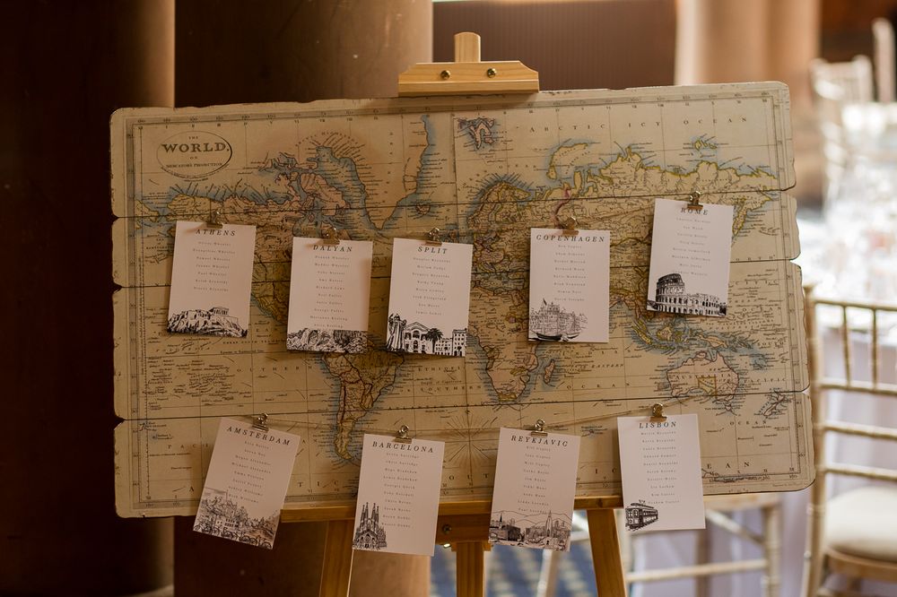 Vintage world map display with photos and cards creates a rustic travel-themed wedding decor backdrop.